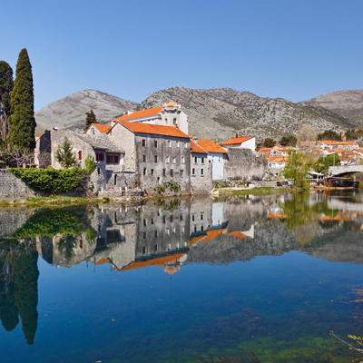 Historische stad Trebinje aan de rivier Trebišnjica met stenen brug en bergen op de achtergrond, Balkan.