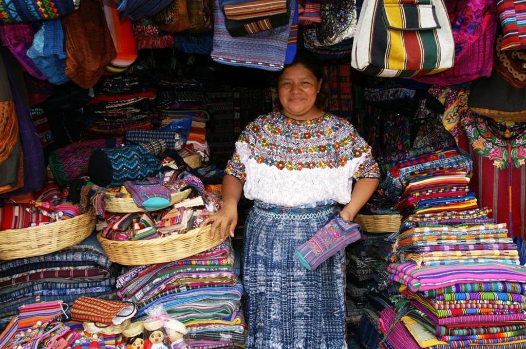 Vrouw bij marktkraam met kleurrijke handgeweven textiel in Guatemala tijdens familiereis Guatemala en Belize.