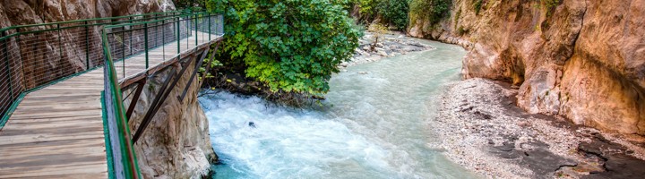 Houten wandelpad langs de Saklikent-kloof met turkooizen rivier tussen steile rotswanden in Turkije.
