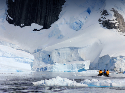 Zodiacboot met reizigers vaart langs ijsbergen en gletsjerwand in Antarctica tijdens de route Antarctica, vliegen en varen.
