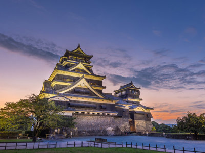 Verlicht Kumamoto-kasteel bij zonsondergang tijdens de Route Japan rondreis.
