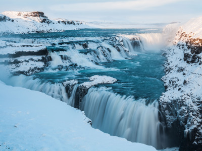Gullfoss-waterval in IJsland in de winter, met besneeuwde kliffen en ijzig blauw rivierwater.