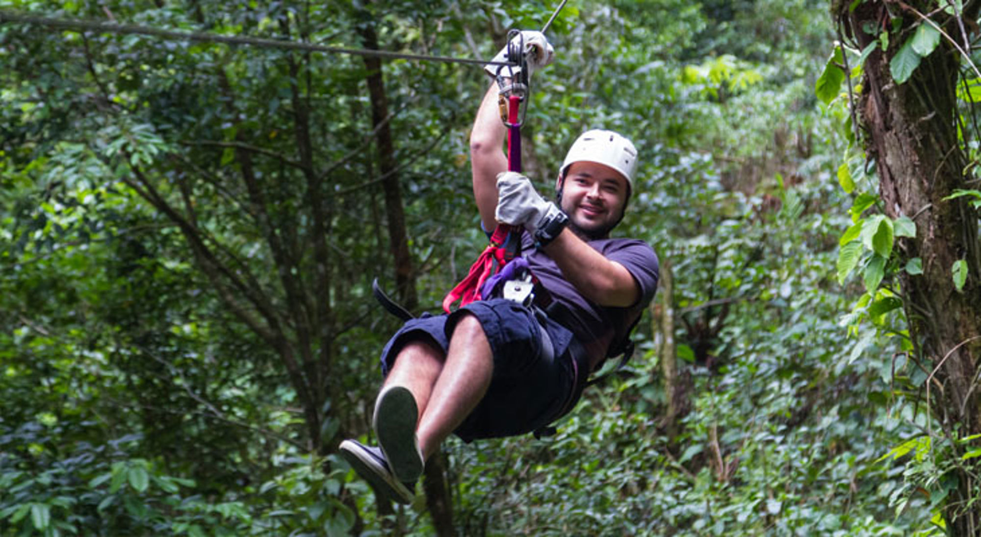 Man tokkelt aan een zipline door het regenwoud in Costa Rica.