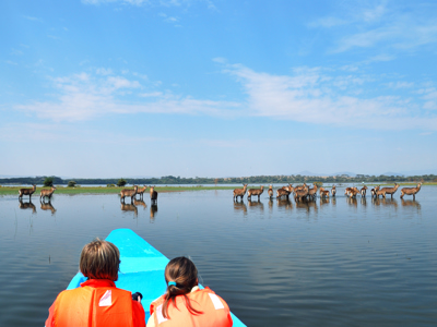 Kinderen in een kano kijken naar een groep waterbokken in het meer tijdens de Route Oost-Afrika.