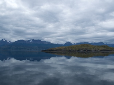 Rustige zee met weerspiegeling van bergen en eiland tijdens de route rondreis Antarctica.