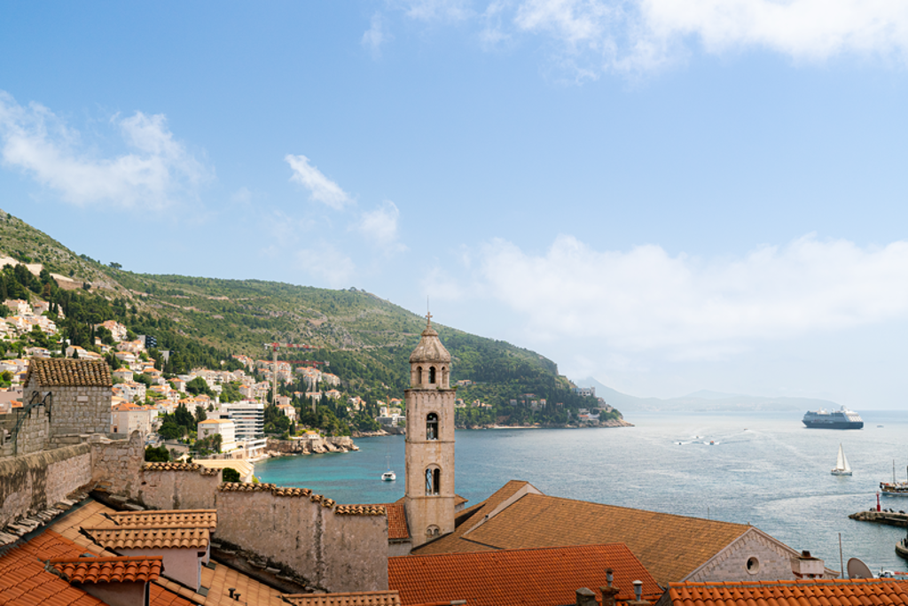 Uitzicht over Dubrovnik met kerktoren, rode daken en de Adriatische Zee tijdens fietsvakantie Balkan.