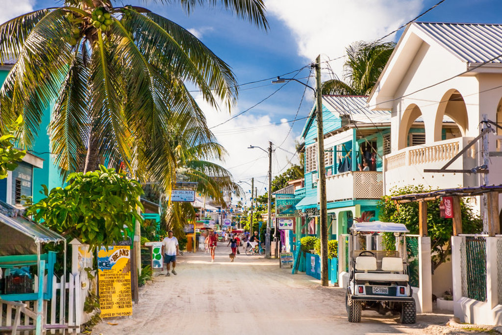 Zandstraat met palmbomen en kleurrijke huizen in Belize, onderdeel van de familiereis Guatemala en Belize.