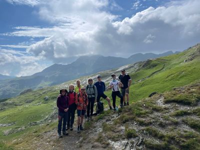 Wandelgroep op bergpad met uitzicht op groene Balkanbergen onder een dramatische wolkenlucht.