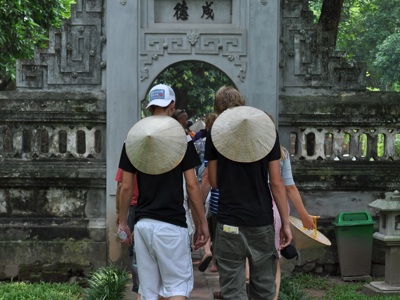 Reizigers met Vietnamese hoeden lopen door een tempelpoort tijdens de Route Vietnam.