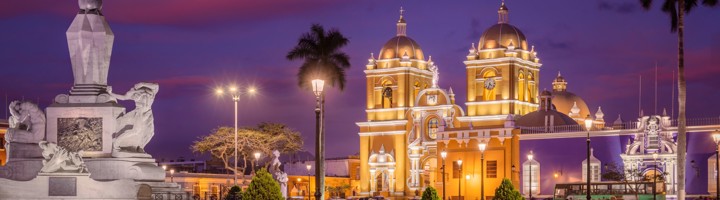 Verlicht Plaza de Armas in Trujillo met de kathedraal en het Vrijheidsmonument bij zonsondergang.