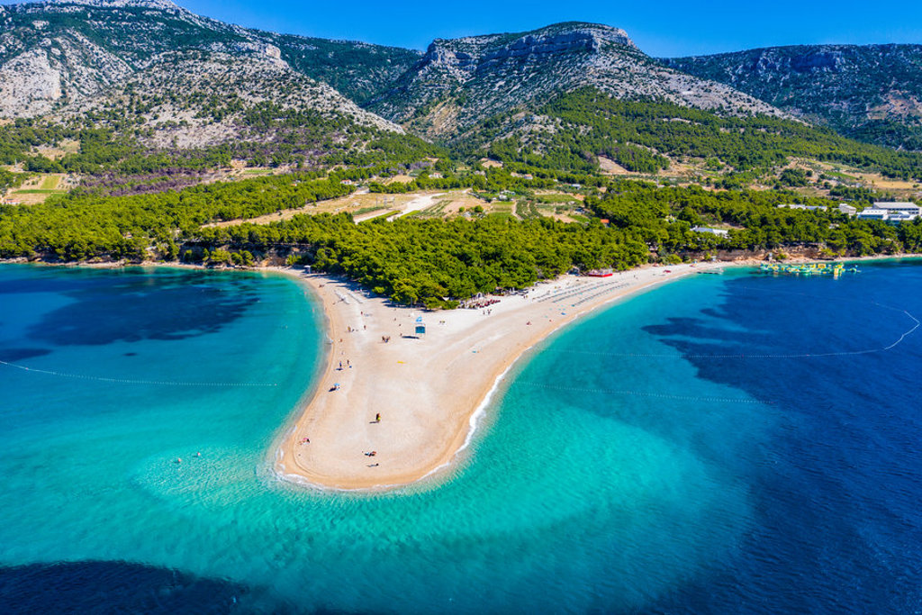 Zlatni Rat strand op Brač, Kroatië, met turquoise zee en bergen tijdens fietsvakantie Balkan.