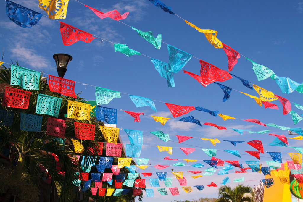 Kleurrijke Mexicaanse papel picado-slingers wapperen boven de straat tijdens de 22-35ers reis Mexico.