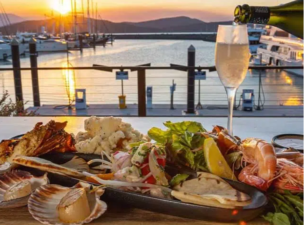 Zeevruchtenplank met champagne bij zonsondergang in een jachthaven tijdens een 22-35ers reis door Australië.