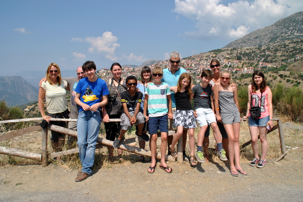 Groep reizigers tijdens familiereis Noord-Griekenland bij uitzichtpunt met bergdorp op de achtergrond.