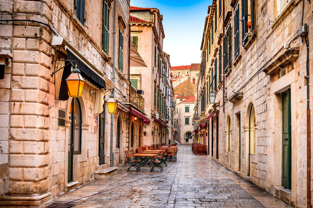 Smalle straat met stenen gebouwen en terrassen in de oude stad van Dubrovnik tijdens een 22-35ers reis Balkan.