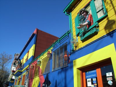 Kleurrijke huizen in La Boca, Buenos Aires, met felgekleurde gevels en figuren bij de ramen.