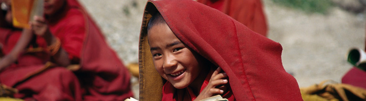 Lachende jonge monnik in rood gewaad in Tibet tijdens een rondreis.