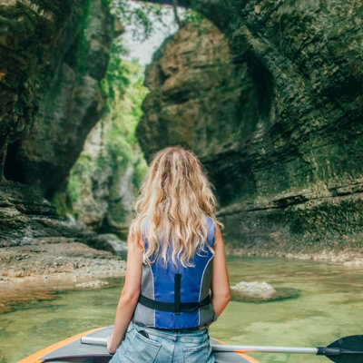 Vrouw op een raft in een smalle kloof met rotswanden en helder water in Georgië.