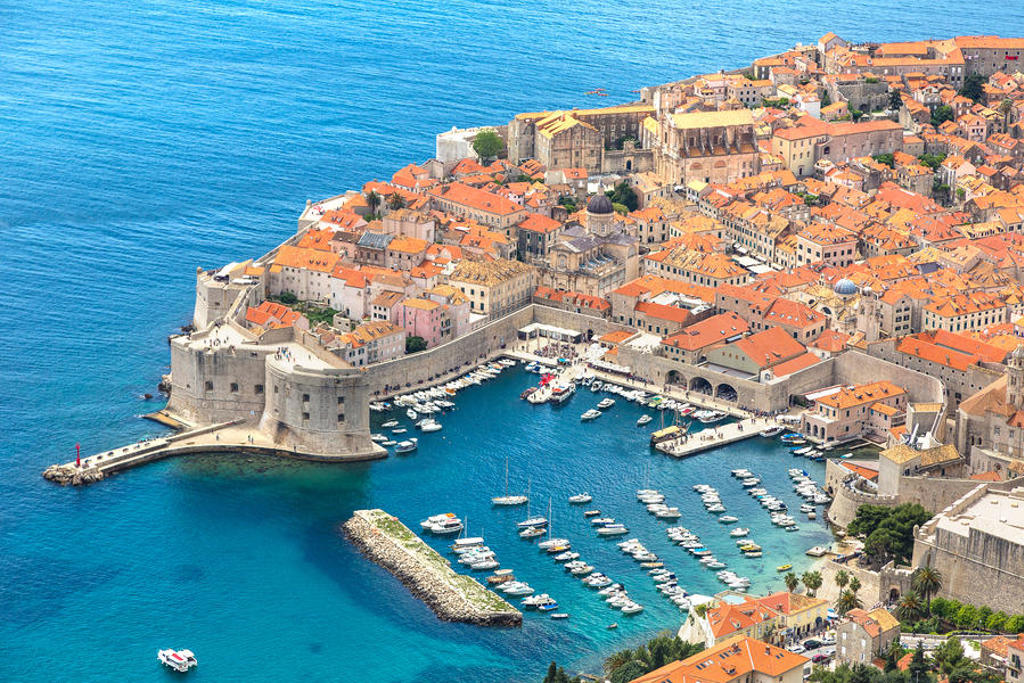 Uitzicht op de ommuurde oude stad Dubrovnik met haven en bootjes aan de Adriatische Zee.