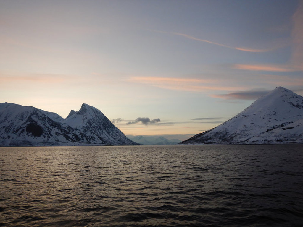Besneeuwde bergen langs een Noorse fjord bij zonsondergang tijdens de groepsrondreis met zeilschip Antigua.