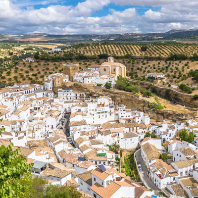Wit Andalusisch dorp op een rots met uitzicht op olijfgaarden, Spanje.