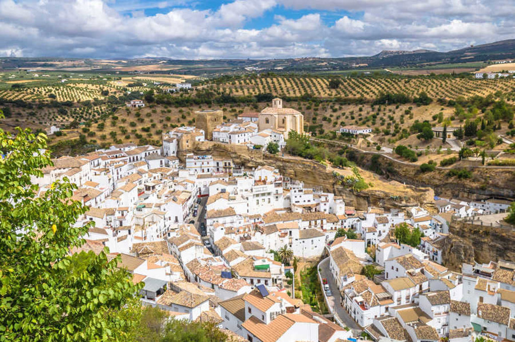 Wit Andalusisch dorp op een rots met uitzicht op olijfgaarden, Spanje.