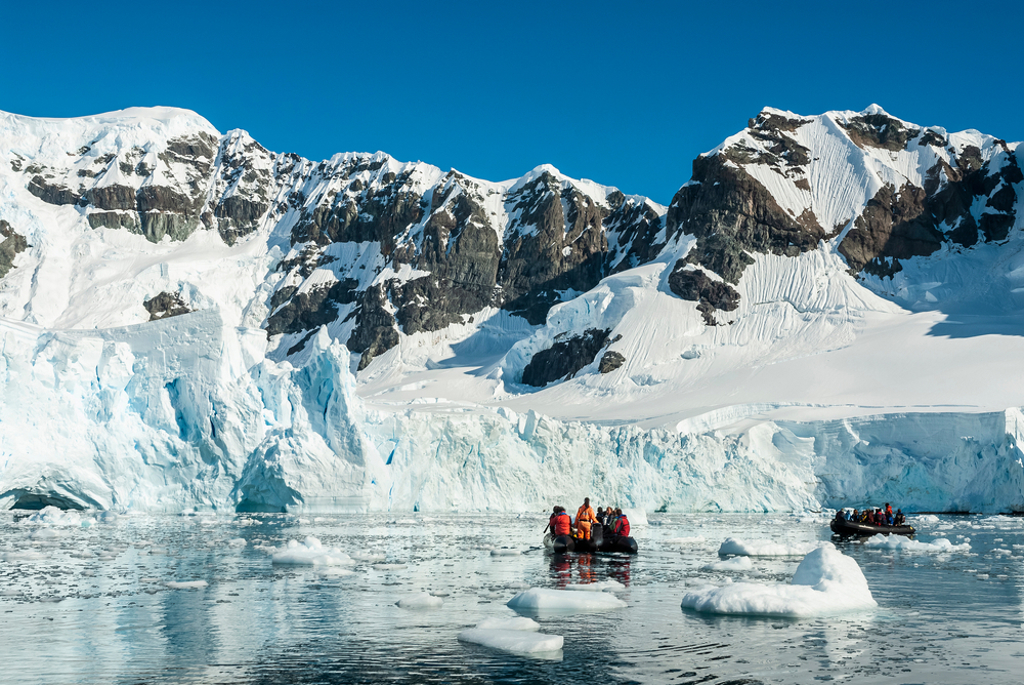 Zodiacboot met reizigers tussen ijsbergen en gletsjers tijdens groepsrondreis Antarctica.