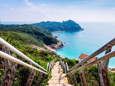 Trap naar een baai met turquoise zee en groene heuvels aan de kust van Maleisië.