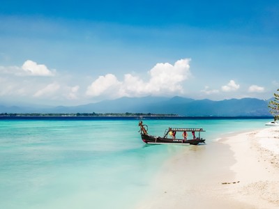 Traditionele boot aan een wit zandstrand met turquoise zee op de Kleine Sunda Eilanden, Indonesië.