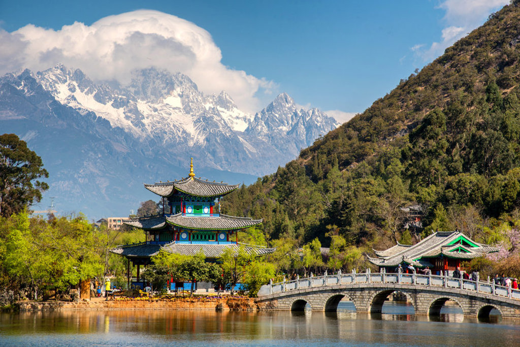 Traditionele Chinese pagode en stenen brug bij een meer, met besneeuwde bergen op de achtergrond in China.
