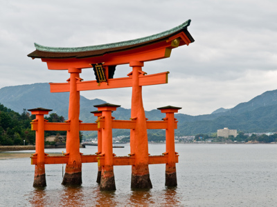 Rode torii-poort in zee bij Miyajima, met bergen op de achtergrond.