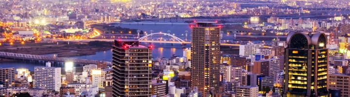 Avondpanorama van de skyline van Osaka met verlichte wolkenkrabbers, rivier en bruggen.