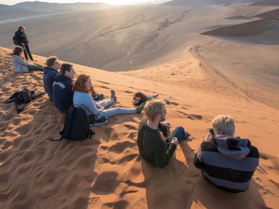 Reizigers genieten van zonsondergang op de zandduinen van de Namibwoestijn bij Sossusvlei.