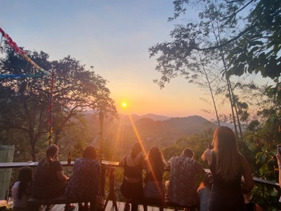 Reizigers kijken vanaf een terras naar de zonsondergang boven de groene bergen in Colombia.