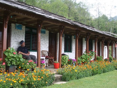 Traditioneel Nepalese lodge met veranda en bloeiende tuin langs de Route Nepal.
