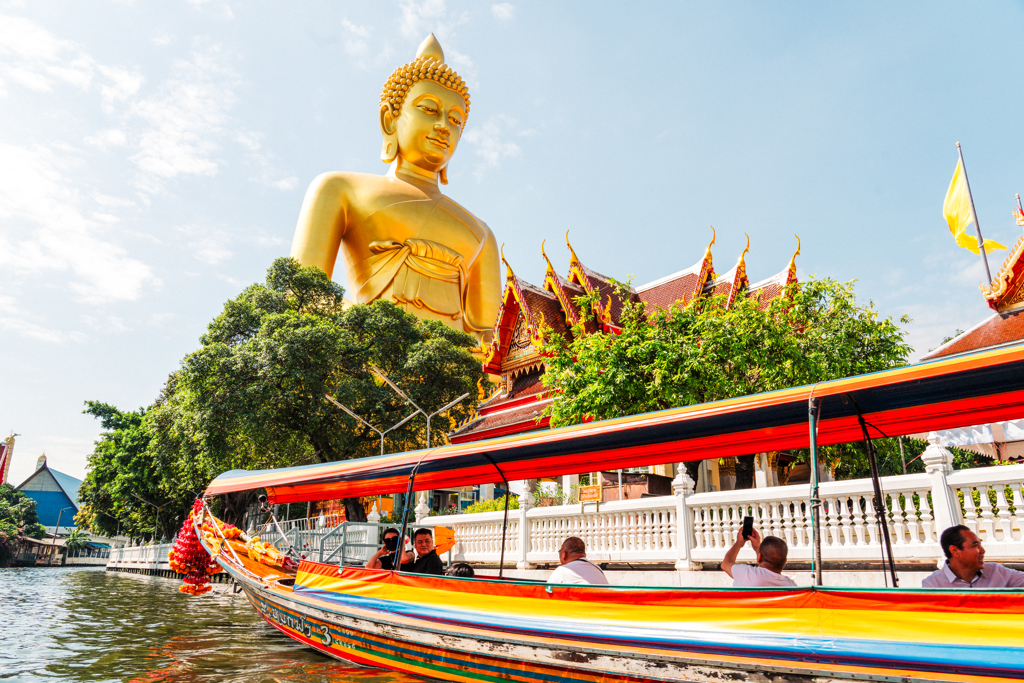Boottocht langs een tempel met groot gouden Boeddhabeeld in Thailand tijdens een 22-35ers reis.