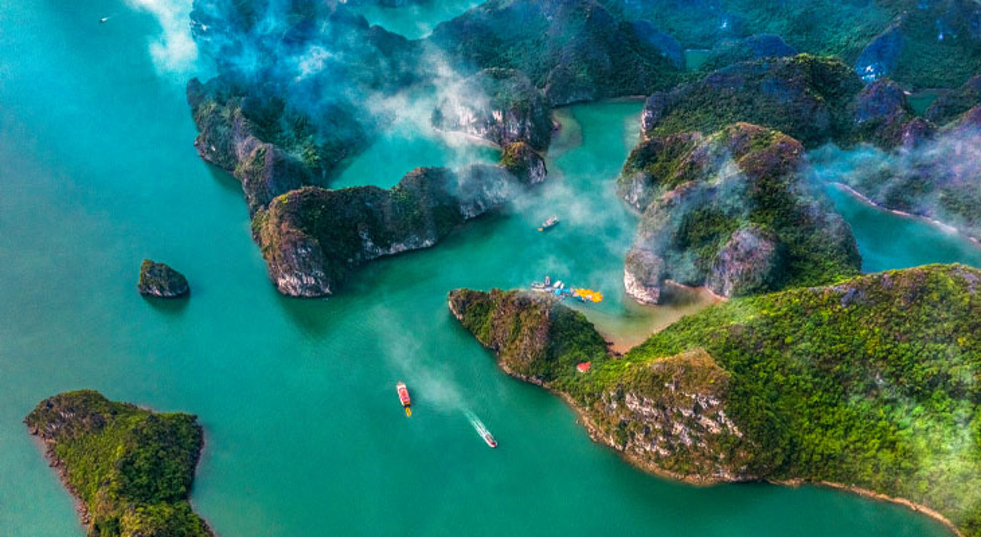 Ha Long Bay in Vietnam met kalkstenen eilanden, turquoise water en boten tussen de rotsen.