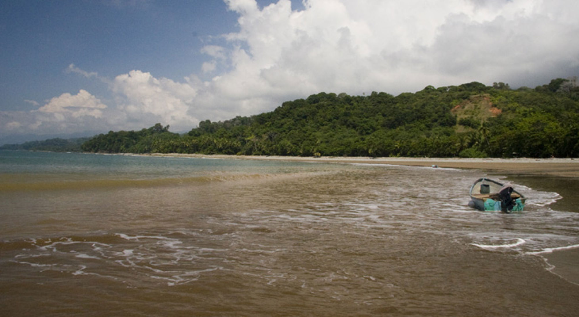 Bootje op een rustig strand met tropisch regenwoud aan de kust in Costa Rica.