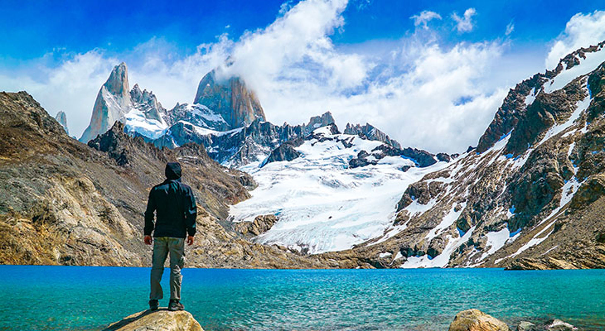 Wandelaar bij turquoise bergmeer met gletsjer en granieten pieken in Patagonië.