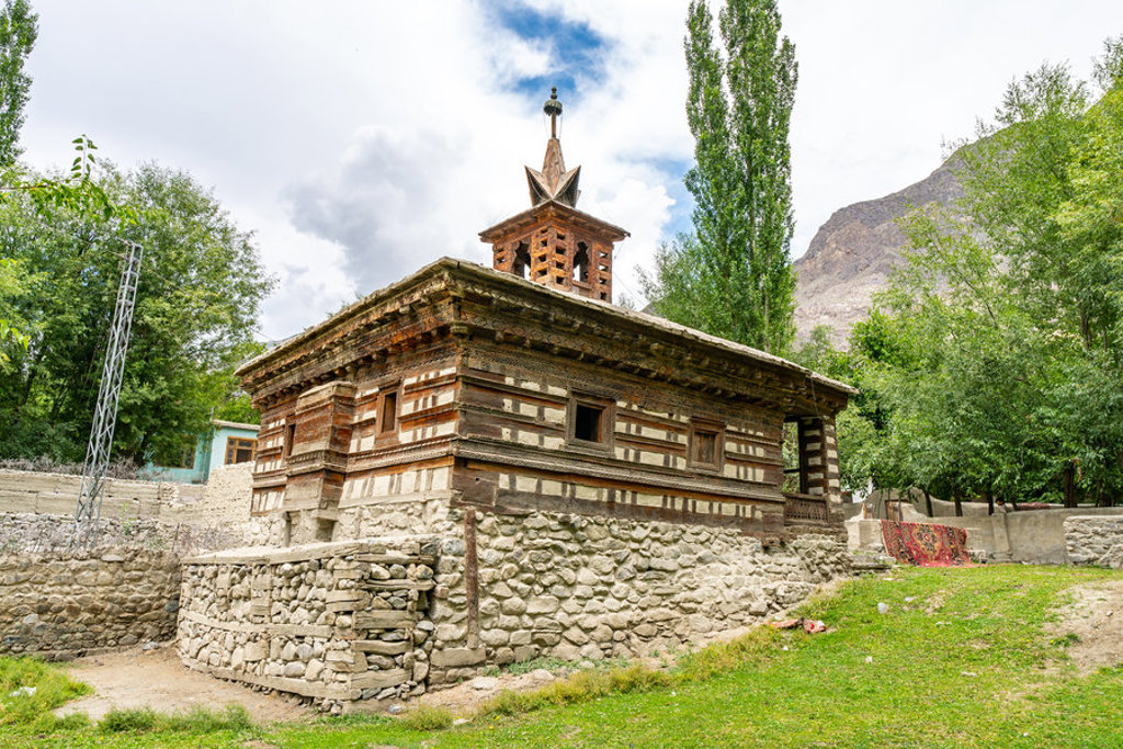 Traditionele houten moskee in de Hunza-vallei, Baltistan, Pakistan, omringd door bomen en bergen.