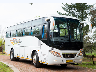 Witte tourbus voor vervoer in Zuid-Afrika op een landweg.
