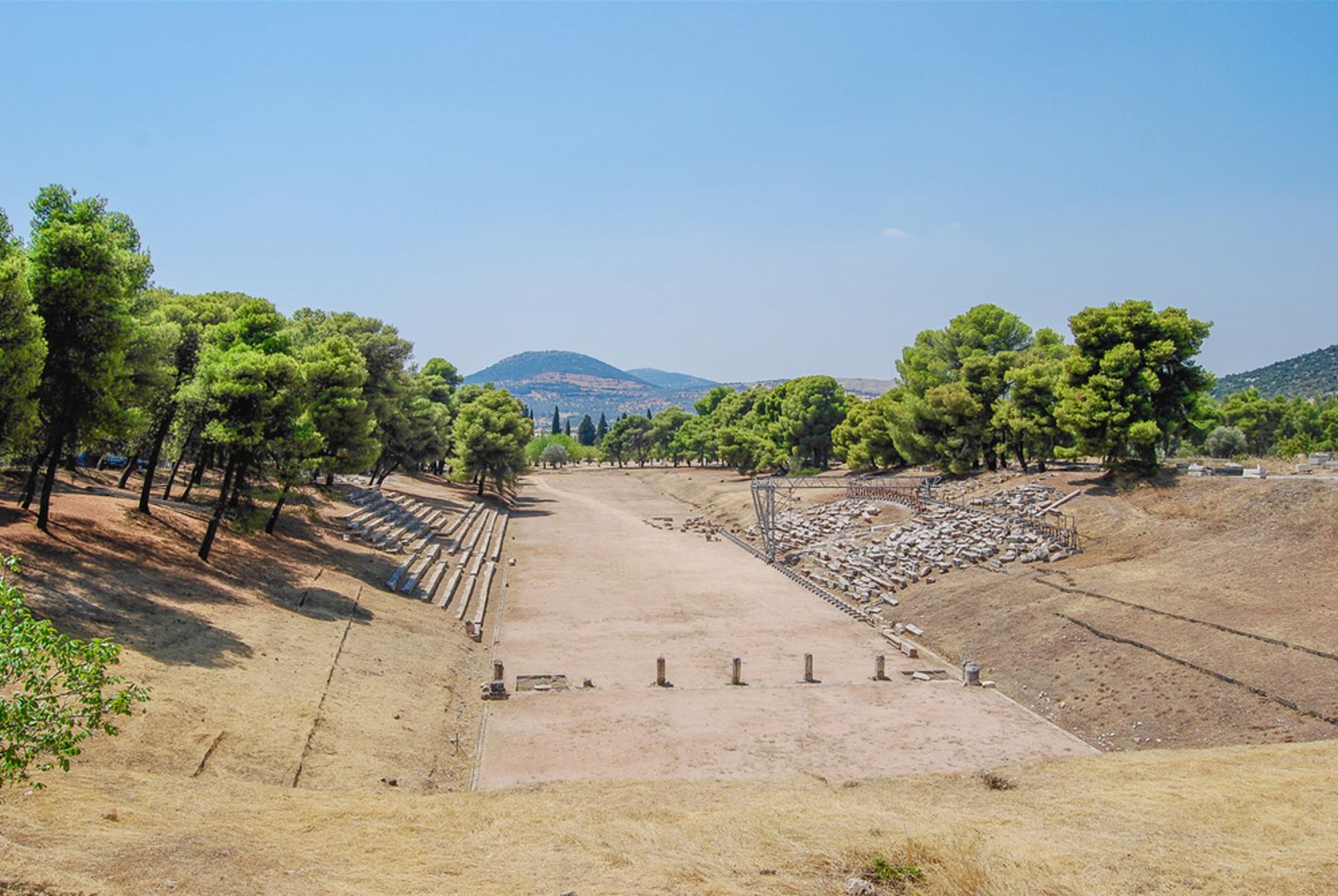 Panathinaiko Stadion in Athene, Griekenland, met zandige arena en tribunes tussen groene bomen.