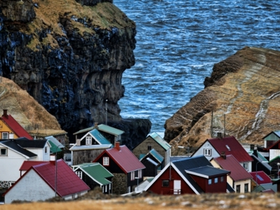 Kleurrijk dorp met huizen aan de kust tussen steile kliffen en de Atlantische Oceaan op de route Aberdeen naar Spitsbergen.