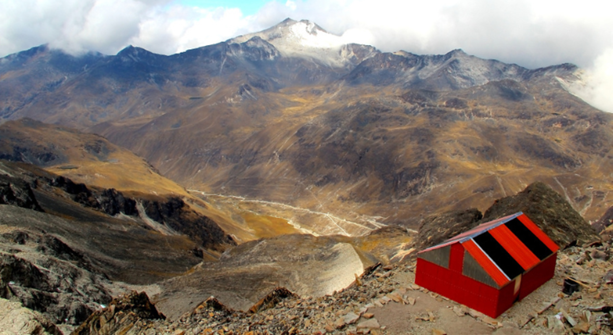 Uitzicht op het Andesgebergte in Bolivia met een rood bergschuilhutje op de voorgrond.