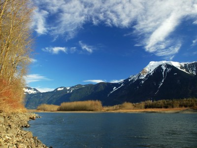 Rivierlandschap met besneeuwde bergen en blauwe lucht langs de Route Canada.