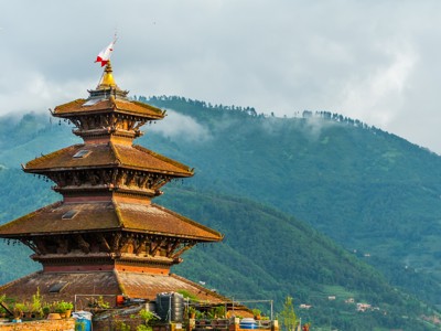 Traditionele Nepalese tempel met pagodedak tegen groene heuvels en nevel, route Noord-India en Nepal.