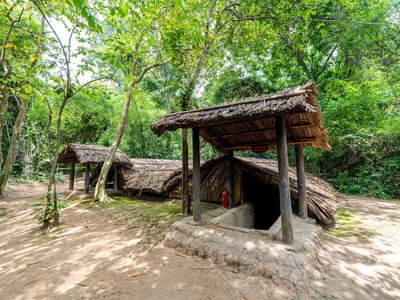 Cu Chi-tunnels in Vietnam met camouflaged ingang onder rieten afdak in het bos.