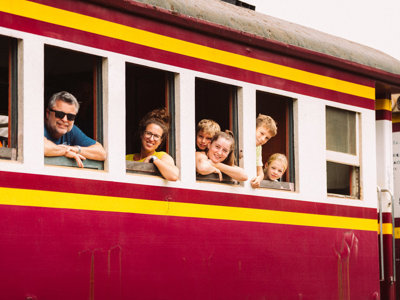 Gezin kijkt uit het raam van een kleurrijke trein tijdens familiereis Thailand, route van 15 dagen.
