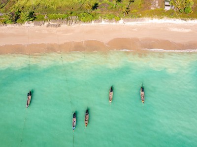 longtailboten voor een zandstrand met palmen aan de kust van Thailand, route mei t/m september.