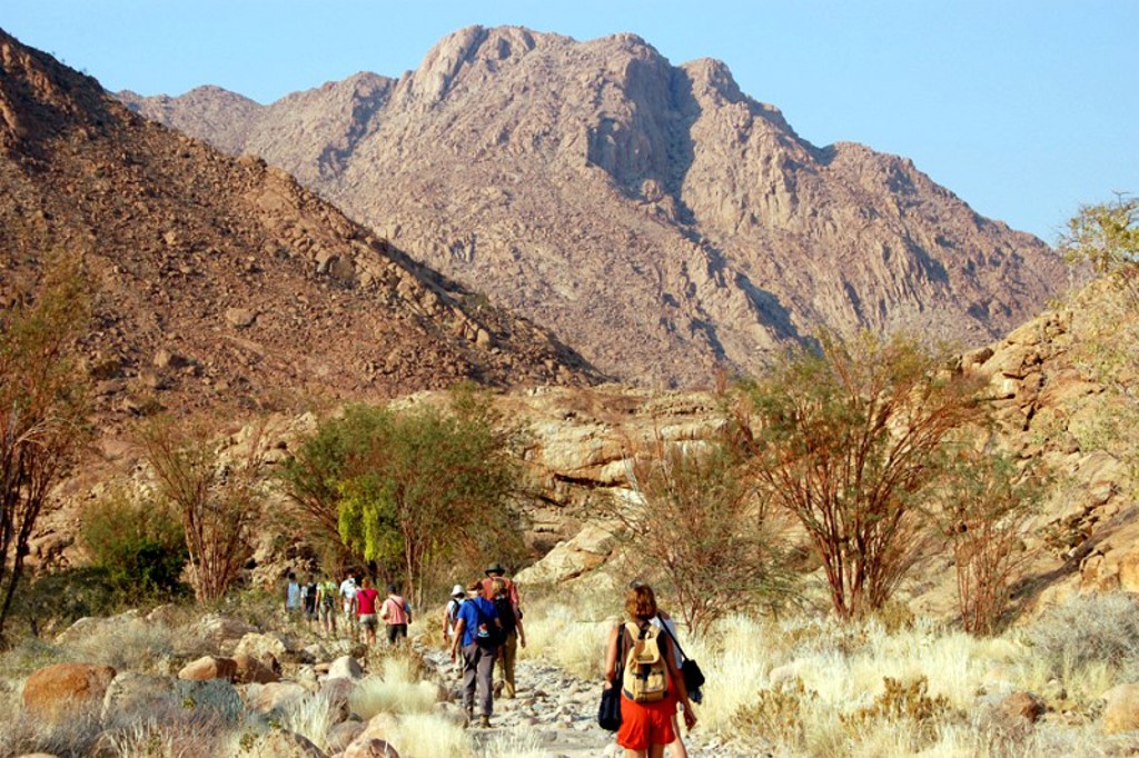 Wandelaars tijdens groepsrondreis Zuidelijk Afrika in rotsachtig berglandschap in Namibië.